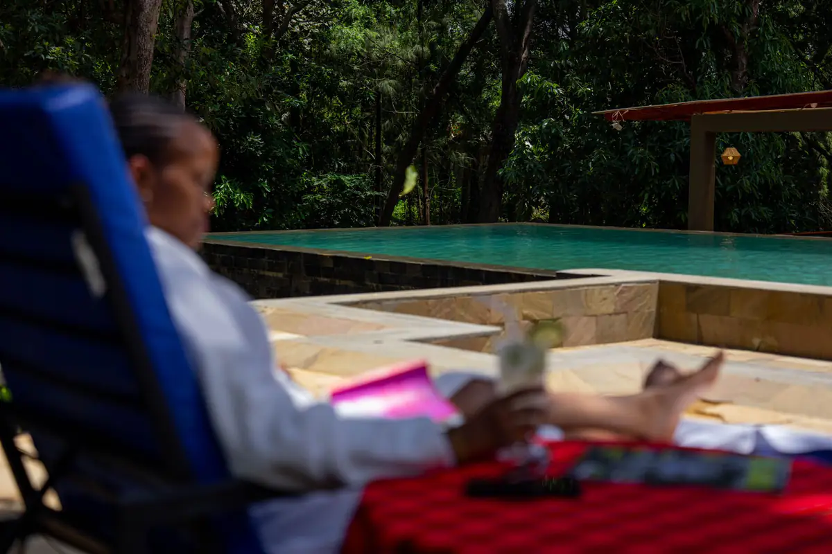 Guest relaxing on a lounger beside the pool at Mvuli Farm Lodge