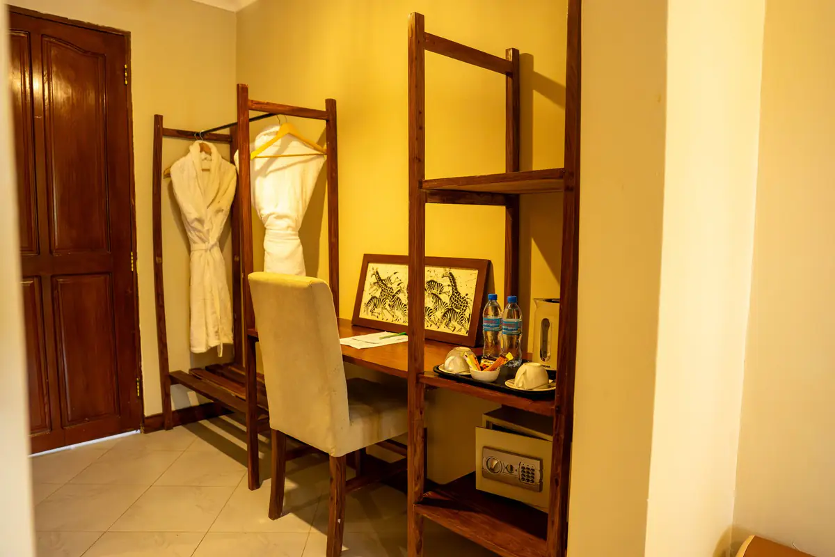 Desk, open wardrobe and bathrobe in a room at Mvuli Farm Lodge